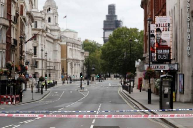 A deserted road leading to the scene where a car crashed into security barriers outside the Houses of Parliament to the right of a bus in London, Tuesday, Aug. 14, 2018. (AP Photo/Frank Augstein)