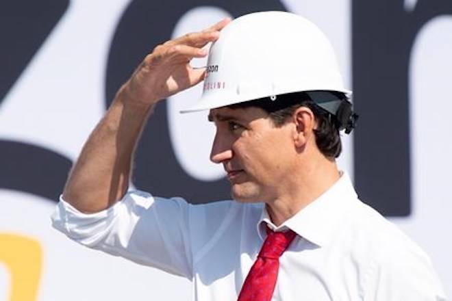 Prime Minister Justin Trudeau adjusts his hat as he participates in a ground breaking ceremony for an Amazon distribution centre in Ottawa, Monday August 20, 2018. THE CANADIAN PRESS/Adrian Wyld