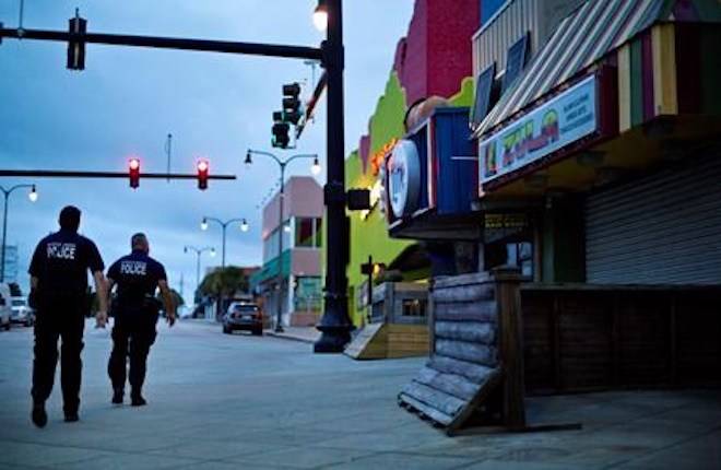 Police patrol past boarded up shops along the boardwalk in Myrtle Beach, S.C., Thursday, Sept. 13, 2018, as Hurricane Florence approaches the east coast. (AP Photo/David Goldman)