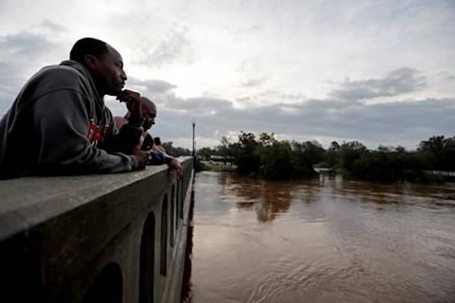 Gerald Generette, left, and Maurice Miller look onto the Cape Fear River as it continues to rise in the aftermath of Florence in Fayetteville, N.C., Monday, Sept. 17, 2018. (AP Photo/David Goldman)