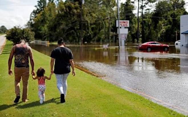 A couple walks with their daughter after checking on their flooded home in the aftermath of Hurricane Florence in Spring Lake, N.C., Monday, Sept. 17, 2018. (AP Photo/David Goldman)