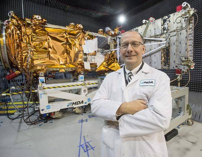 MDA’s President Mike Greenley is seen in front of one of three RADARSAT Constellation Mission spacecrafts being built for the Canadian Space Agency at the company’s facility in Sainte-Anne-de-Bellevue, Quebec on Tuesday January 30, 2018. THE CANADIAN PRESS/Ryan Remiorz