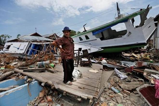 A man stands amid the damage near boats swept ashore by the tsunami in Wani village on the outskirts of Palu, Central Sulawesi, Indonesia, Thursday, Oct. 4, 2018. People living in tents and shelters have little but uncertainty since the powerful earthquake and tsunami hit the city, where death toll rises and efforts to retrieve scores more victims buried deep in mud and rubble were still hampered Thursday by the lack of heavy equipment. (AP Photo/Dita Alangkara)