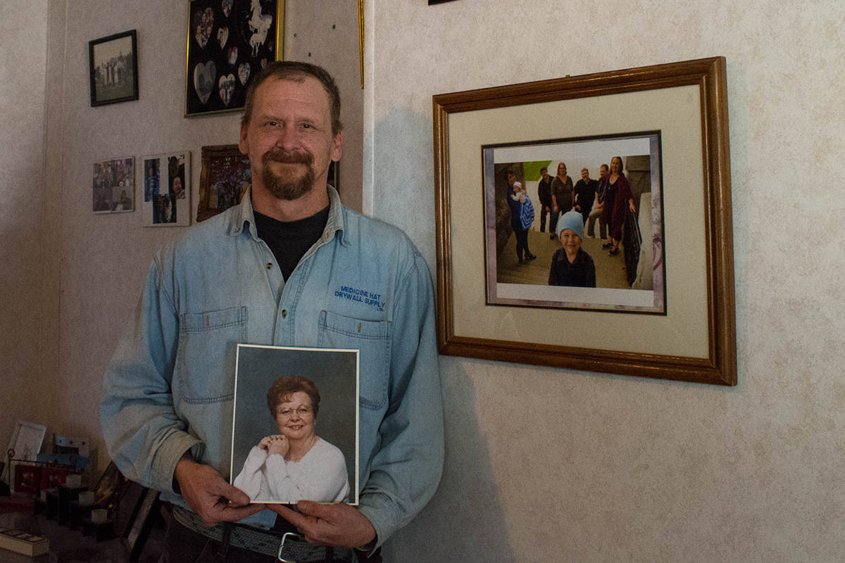 Ross Hurlbert holds a photo of his mother Caroline Hurlbert with pictures of his roommate’s family are in the background. Usually all of them spend Christmas together. However, this Christmas may be different (Liam Harrap/Revelstoke Review).