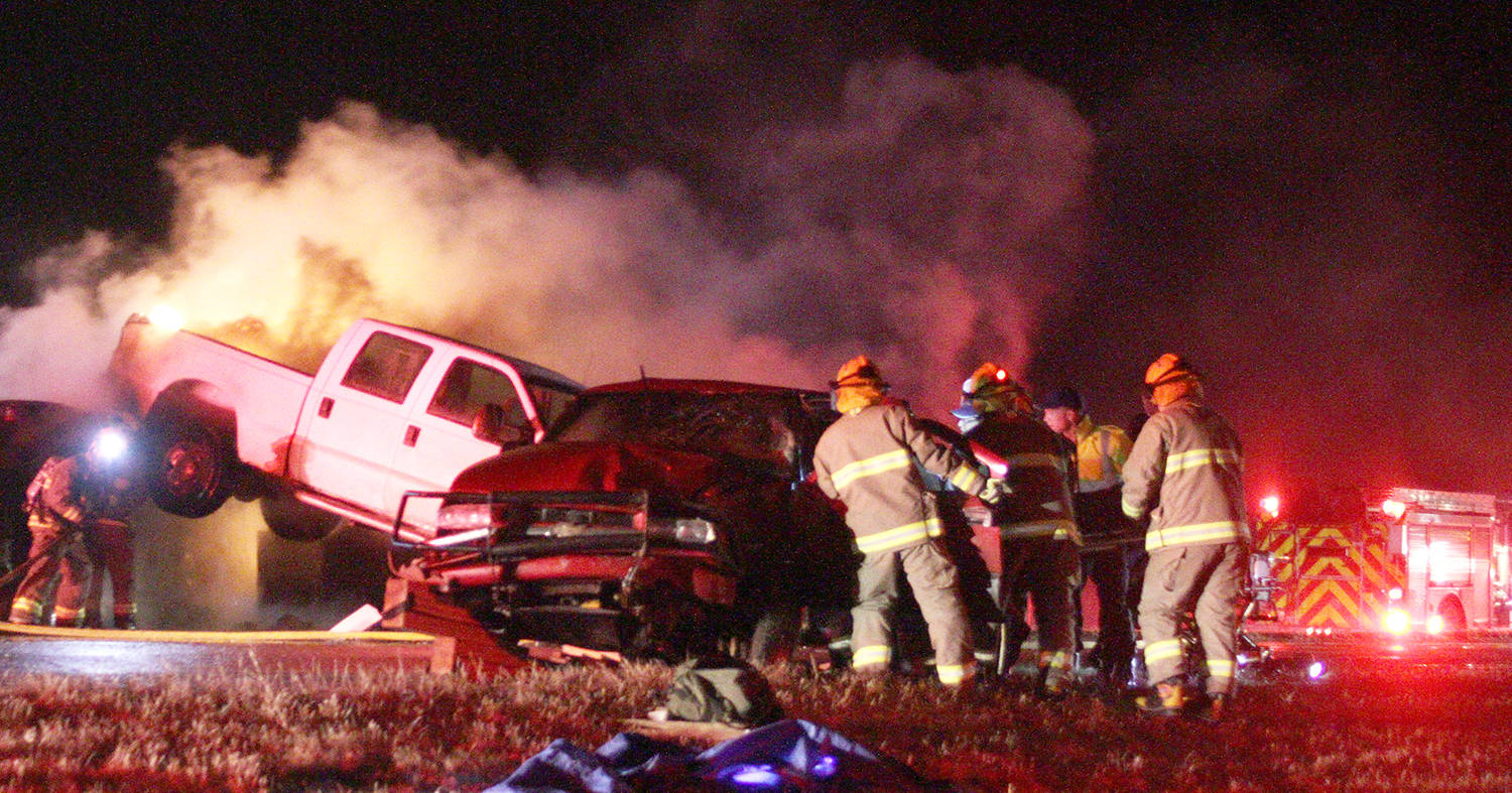 Firefighters work to extricate a woman trapped in a red SUV Friday night on the Highway 2 bridge at the Highway 53 intersection. A truck hauling a trailer collided with a mini-van, which became engulfed in flames, and an SUV. The northbound lanes were closed for about six hours while a collision analyst investigated.                                 Photo by Jeffrey Heyden-Kaye