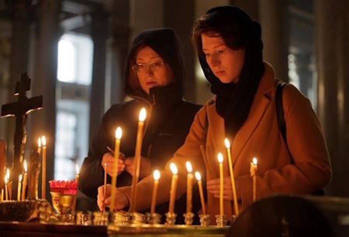 Women light candles in memory of victims of shooting in the vocational college in Kerch, Crimea, in a church in St.Petersburg, Russia, Thursday, Oct. 18, 2018. An 18-year-old student strode into his vocational school in Crimea, Wednesday, then pulled out a shotgun and opened fire, killing 19 students and wounding more than 50 others before killing himself. (AP Photo/Dmitri Lovetsky)
