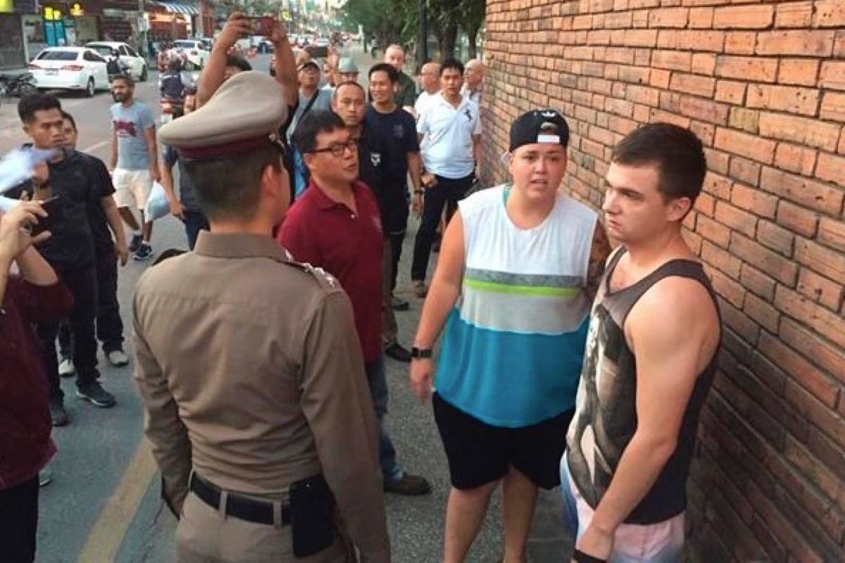 In this Thursday, Oct. 18, 2018, photo, Brit Furlong Lee, right, and Canadian Brittney Lorretta Katherine Schneider, second right, stand in front of Tha Pae Gate in Chiang Mai province, northern Bangkok, Thailand. They face up to 10 years in prison on charges of spraying paint on the ancient wall in northern Thailand, police said Friday. (Chiang Mai News via AP)