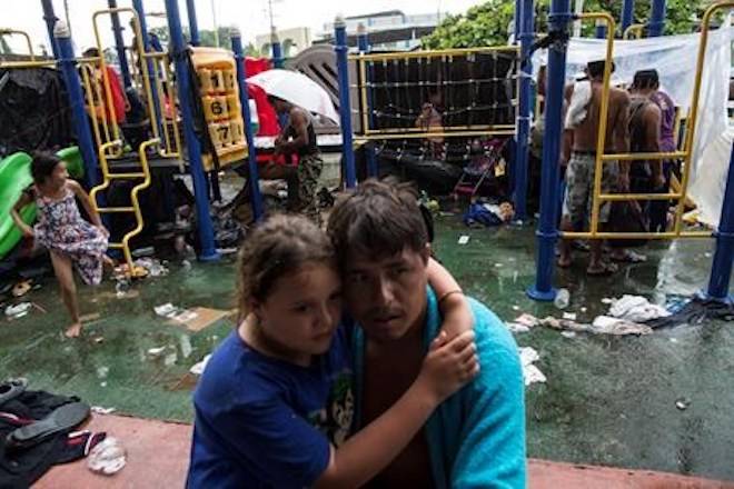 Under rain, people take cover at a makeshift camp set up by a caravan of Central American migrants traveling to the U.S, in Mapastepec, Mexico, Wednesday, Oct. 24, 2018. (AP Photo/Rodrigo Abd)