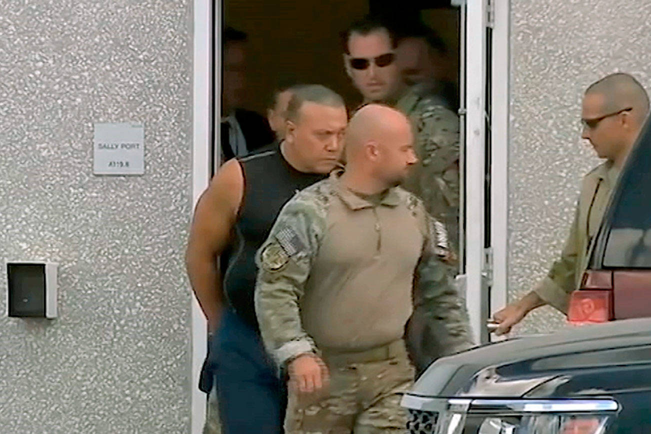This frame grab from video provided by WPLG-TV shows FBI agents escorting Cesar Sayoc, in sleeveless shirt, in Miramar, Fla., on Friday, Oct. 26, 2018. Sayoc is an amateur body builder and former male stripper, a loner with a long arrest record who showed little interest in politics until Donald Trump came along. On Friday, he was identified by authorities as the Florida man who put pipe bombs in small manila envelopes, affixed six stamps and sent them to some of Donald Trump’s most prominent critics. (WPLG-TV via AP)