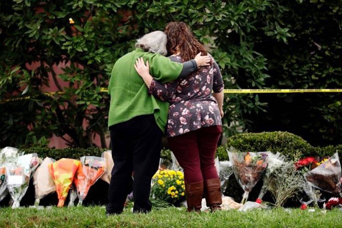 Two people support each other in front of flowers at a makeshift memorial at the Tree of Life Synagogue in Pittsburgh, Sunday, Oct. 28, 2018. Robert Bowers, the suspect in Saturday’s mass shooting at the synagogue, expressed hatred of Jews during the rampage and told officers afterward that Jews were committing genocide and he wanted them all to die, according to charging documents made public Sunday. (Matt Rourke/AP)