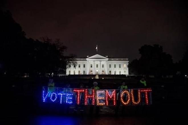 A group of people hold up a sign that reads “Vote Them Out” as they protest in front of the White House the night before midterm election voting begins, Monday, Nov. 5, 2018, in Washington. (AP Photo/Andrew Harnik)