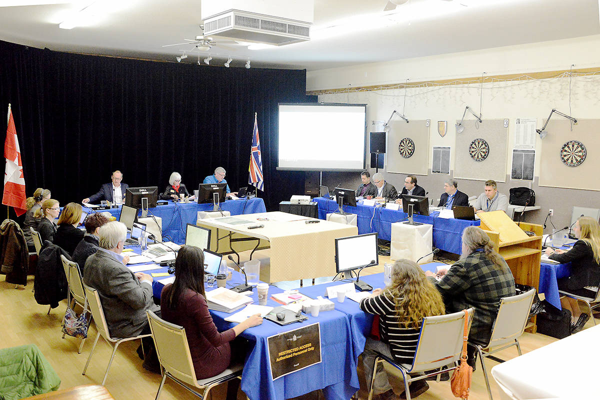 Participants in a detailed route hearing sit at four tables in the Clearwater Legion Hall on Tuesday, March 6. At the far end are three National Energy Board panellists, on the right are five Trans Mountain representatives, staff members from NEB sit on the table on the left, and at the near table are complainants and lawyers.