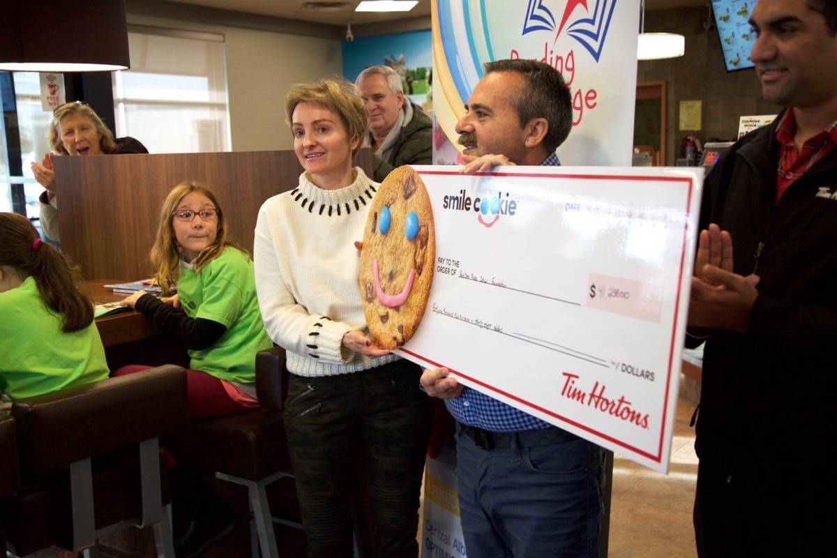 Tim Hortons owners, from left, Suzanne and Abe Robalo and Harpreet Sraon hold up the cheque for $41,238 Wednesday. The money was raised during the annual Smile Cookie campaign and goes to the Foundation for Red Deer Public School’s Reading College program. Robin Grant/Red Deer Express
