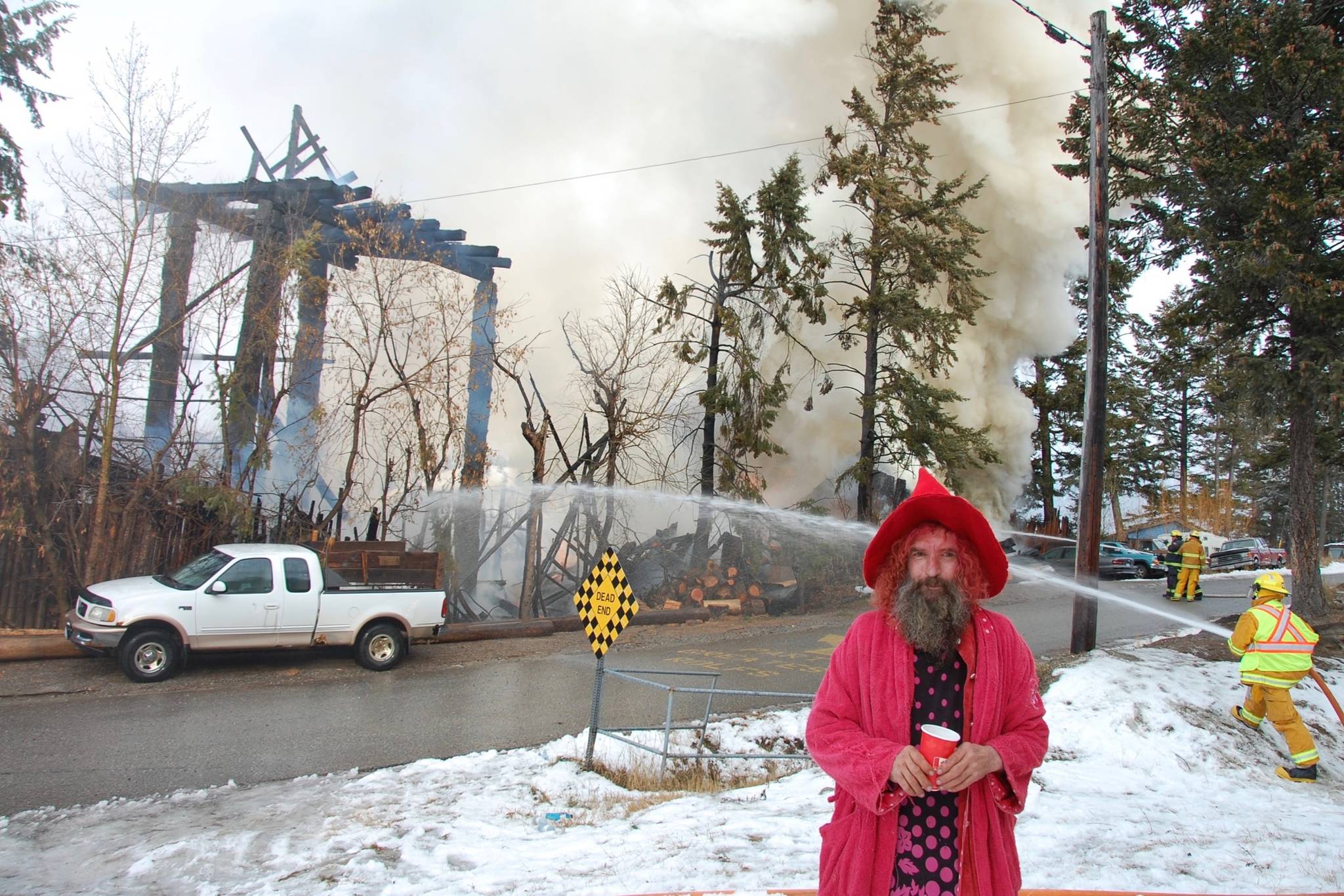 Rolf Heer smiles, cracking jokes with a reporter while behind him, his life’s legacy burns to the ground. Photo by Dauna Ditson