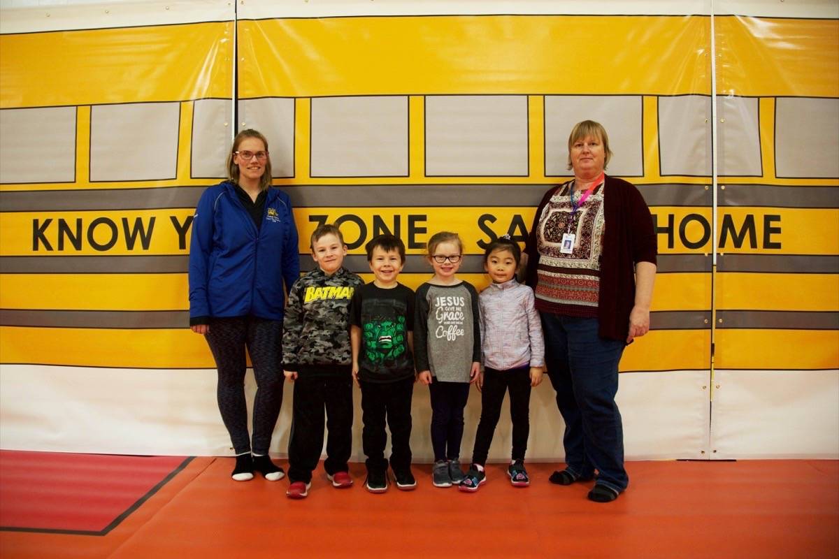 Grade 1 students James McRae, Noah Doucette, Lucy Armstrong and Lia Cho at St. Elizabeth Seton School stand in front of a lifesize bus simulation with instructors Michaelle de Ruiter and Odilia Youngman before learning about bus safety Tuesday. Robin Grant/Red Deer Express
