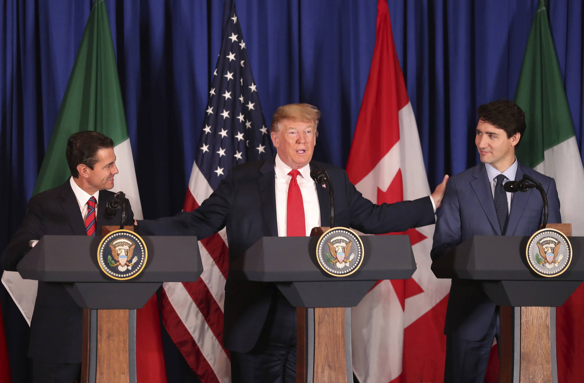 President Donald Trump, center, reaches out to Mexico’s President Enrique Pena Nieto, left, and Canada’s Prime Minister Justin Trudeau as they prepare to sign a new United States-Mexico-Canada Agreement that is replacing the NAFTA trade deal, during a ceremony at a hotel before the start of the G20 summit in Buenos Aires, Argentina, Friday, Nov. 30, 2018. The USMCA, as Trump refers to it, must still be approved by lawmakers in all three countries. (AP Photo/Martin Mejia)