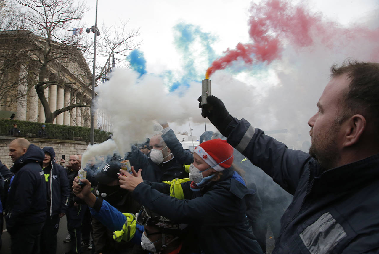 Ambulance workers hold flares outside the National Assembly in Paris, Monday, Dec. 3, 2018. Ambulance workers took to the streets and gathered close to the National Assembly in downtown Paris to complain about changes to working conditions as French Prime Minister Edouard Philippe is holding crisis talks with representatives of major political parties in the wake of violent anti-government protests that have rocked Paris. (AP Photo/Michel Euler)