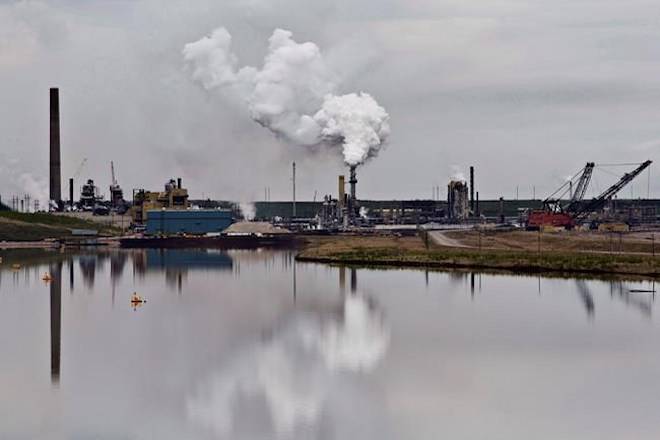 The Syncrude oil sands extraction facility is reflected in a tailings pond near the city of Fort McMurray, Alta., on June 1, 2014. Canadian environment groups are at the global climate change conference in Poland today calling out the federal government for allowing the oil and gas industry to systematically weaken Canada’s efforts to be a climate leader. Environmental Defence and Stand Earth are among the groups releasing a report which shows emissions from the oil and gas sector continue to rise and intensive lobbying from the industry means about 80 per cent of those emissions will be exempt from the carbon price. THE CANADIAN PRESS/Jason Franson