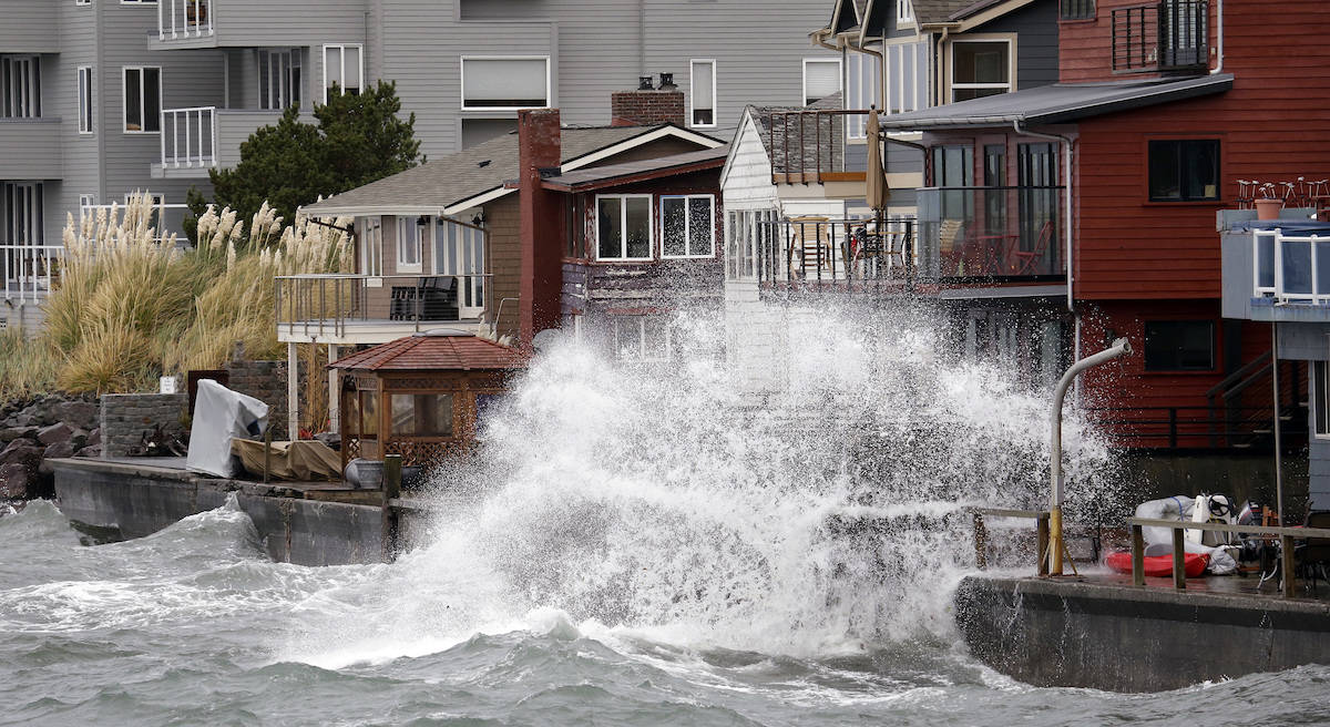 Waves hitting a breakwater send salt spray onto homes along Puget Sound in a windstorm Monday, Nov. 13, 2017, in Seattle. File photo. (AP Photo/Elaine Thompson)