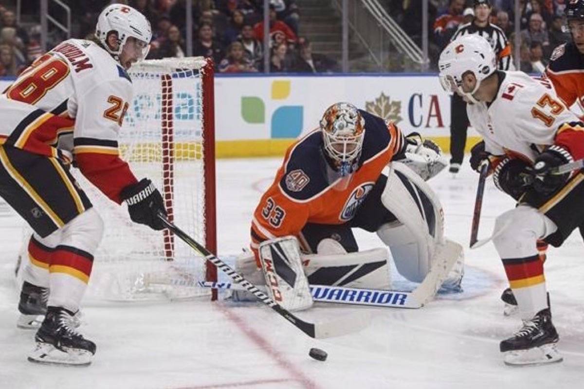 Calgary Flames ’ Elias Lindholm (28) is stopped by Edmonton Oilers’ goalie Cam Talbot (33) as Johnny Gaudreau (13) looks for the loose puck during third period NHL preseason action in Edmonton on Saturday September 29, 2018. (THE CANADIAN PRESS/Jason Franson)