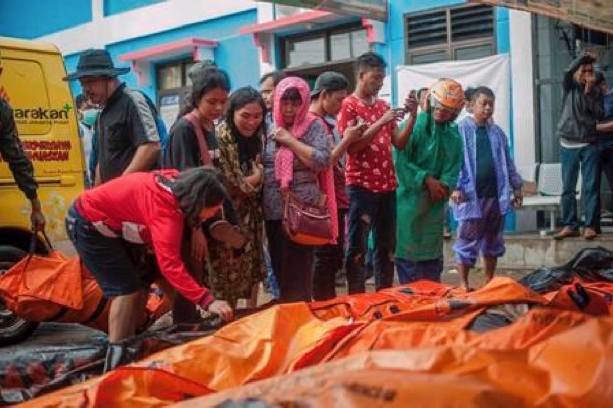 In this Sunday, Dec. 23, 2018, photo, People search for relatives among the bodies of tsunami victims in Carita, Indonesia. The tsunami that hit the coasts of Indonesian islands along the Sunda Strait was not big but it was destructive. The waves smashed onto beaches in the darkness Saturday night without warning, ripping houses and hotels from their foundations in seconds and sweeping terrified concertgoers into the sea. (AP Photo/Fauzy Chaniago)