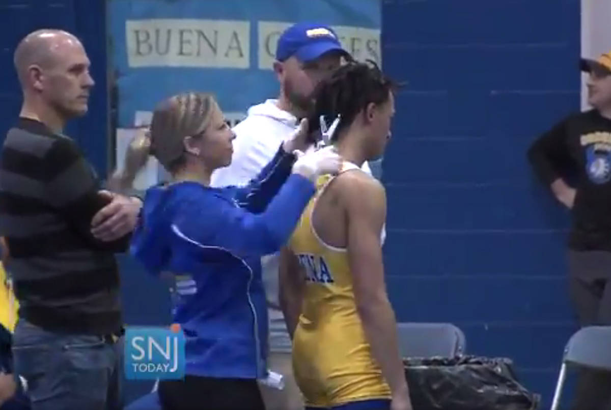 In this image taken from a Wednesday, Dec. 19, 2018 video provided by SNJTODAY.COM, Buena Regional High School wrestler Andrew Johnson is declared the winner after his match in in Buena, N.J. Before the match a referee told Johnson he would forfeit his bout if he didn’t have his dreadlocks cut off. Johnson had his hair cut minutes before the match and a SNJ Today reporter tweeted video of the incident. The state’s Interscholastic Athletic Association says they are recommending the referee not be assigned to any event until the matter has been reviewed more thoroughly. (Michael Frankel/SNJTODAY.COM viavAP)