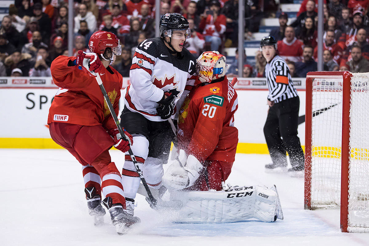 Canada’s Maxime Comtois (14) bumps into Russia goalie Pyotr Kochetkov (20) after the puck deflected wide of the goal while Russia’s Alexander Romanov, left, defends during second period IIHF world junior hockey championship action in Vancouver on Monday, Dec. 31, 2018. (Darryl Dyck/The Canadian Press)