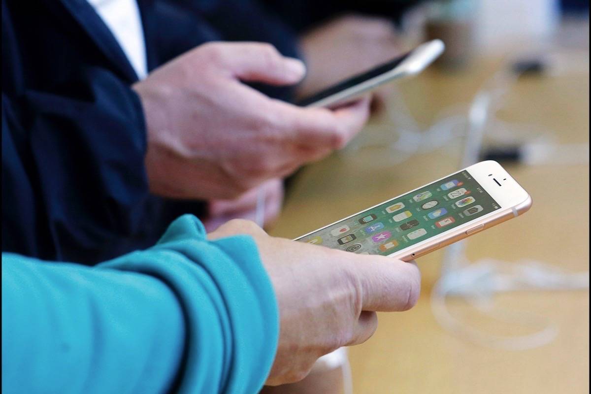 FILE - In this Sept. 22, 2017, file photo, customers look at iPhone 8 and iPhone 8 Plus phones at an Apple Store in San Francisco. (AP Photo/Jeff Chiu)