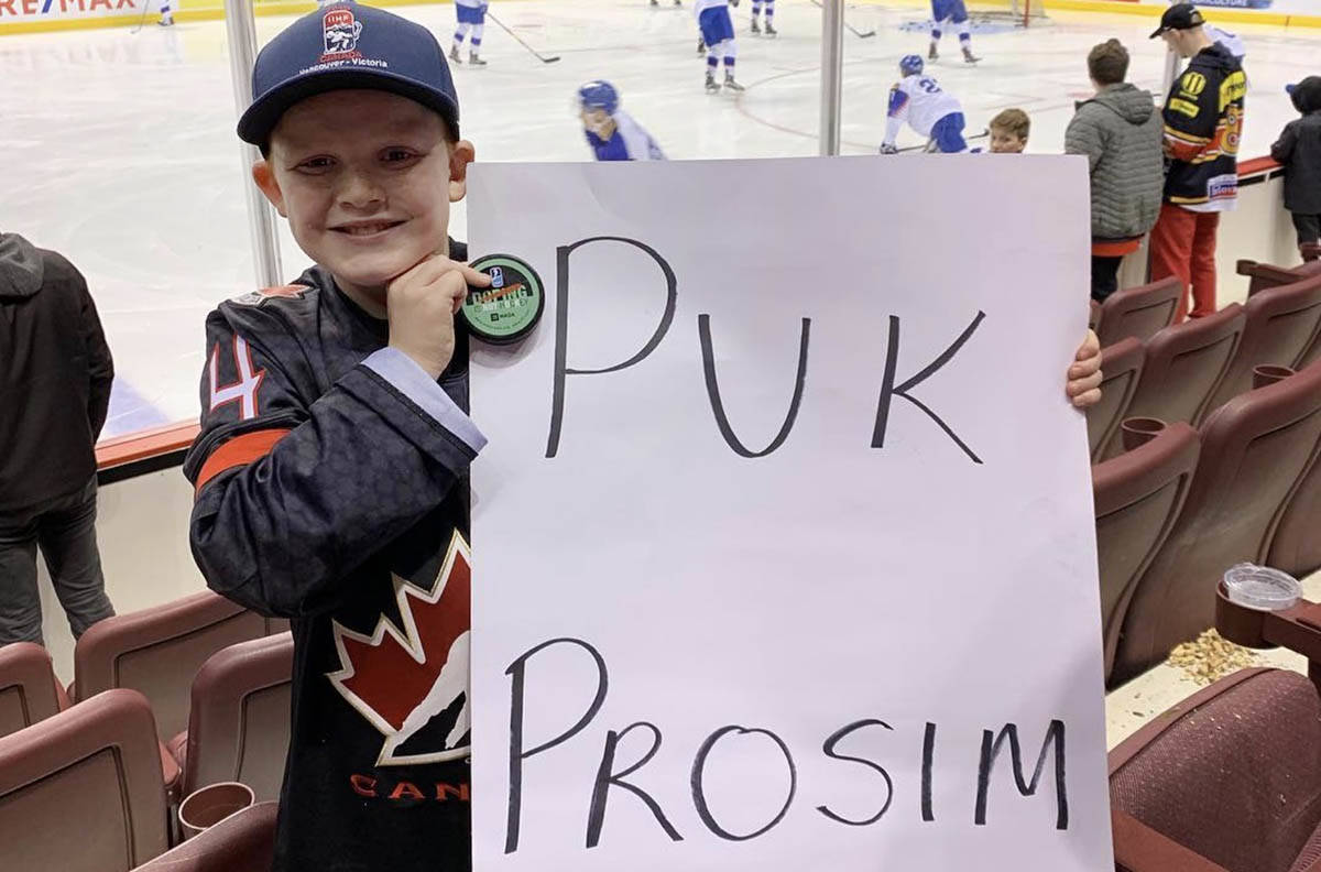 Grayson Boe, 10, with his sign and hockey puck he was thrown from Andrej Kolllar (27) from Team Slovakia (Charlene Boe/Instagram)