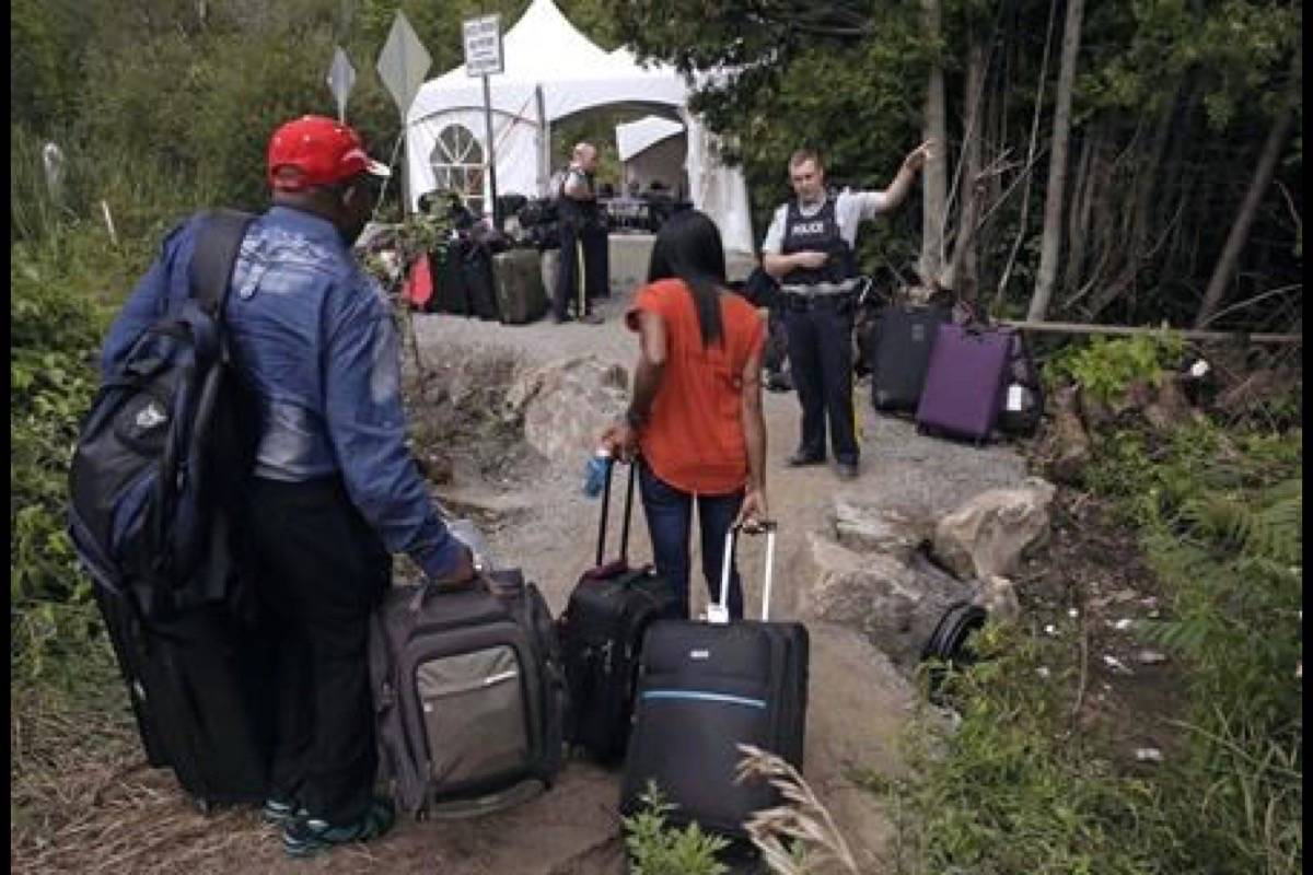 In this Aug. 7, 2017 file photo, an RCMP officer informs a migrant couple of the location of a legal border station, shortly before they illegally crossed from Champlain, N.Y., to Saint-Bernard-de-Lacolle, Quebec, using Roxham Road. The arms-length agency that processes refugee claims in Canada estimated it would need twice as much money as it will ultimately receive to significantly tackle a major backlog in asylum claims, caused in part from an influx of irregular migrants. (THE CANADIAN PRESS/AP/Charles Krupa)