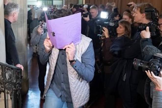 A defendant covers his face when arriving at the court in Berlin, Germany, Thursday, Jan. 10, 2019 for the first day of the trial over the brazen theft of a 100-kilogram (221-pound) Canadian gold coin from a Berlin museum. (Paul Zinken/dpa via AP)