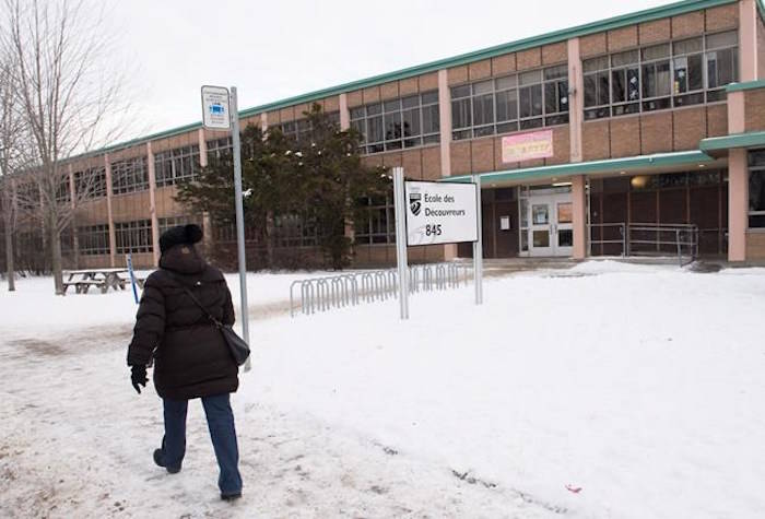 A woman walks by Ecole des Decouvreurs in the Montreal borough of Lasalle where children and staff were evacuated from the elementary school after a carbon monoxide leak on Monday, January 14, 2019; THE CANADIAN PRESS/Graham Hughes