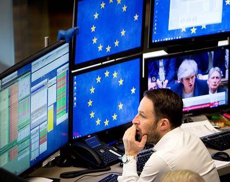 A computer screen shows news about the Brexit with Prime Minister Theresa May as a broker watches his screens at the stock market in Frankfurt, Germany, Wednesday, Jan. 16, 2019. (AP Photo/Michael Probst)