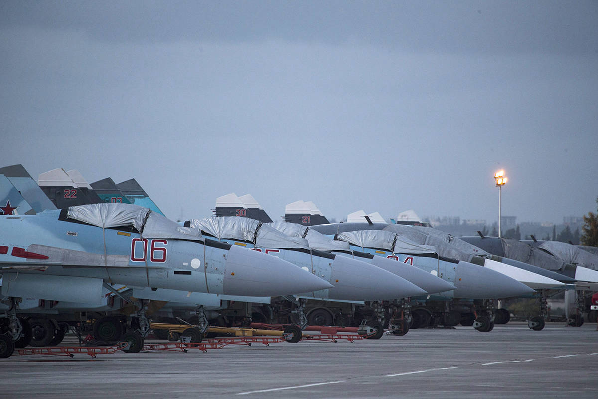 FILE - In this file photo taken on Friday, March 4, 2016, Russian Su-27 fighter jets and Su-34 bomber, right in the back, are parked at Hemeimeem air base in Syria. (AP Photo/Pavel Golovkin, File)