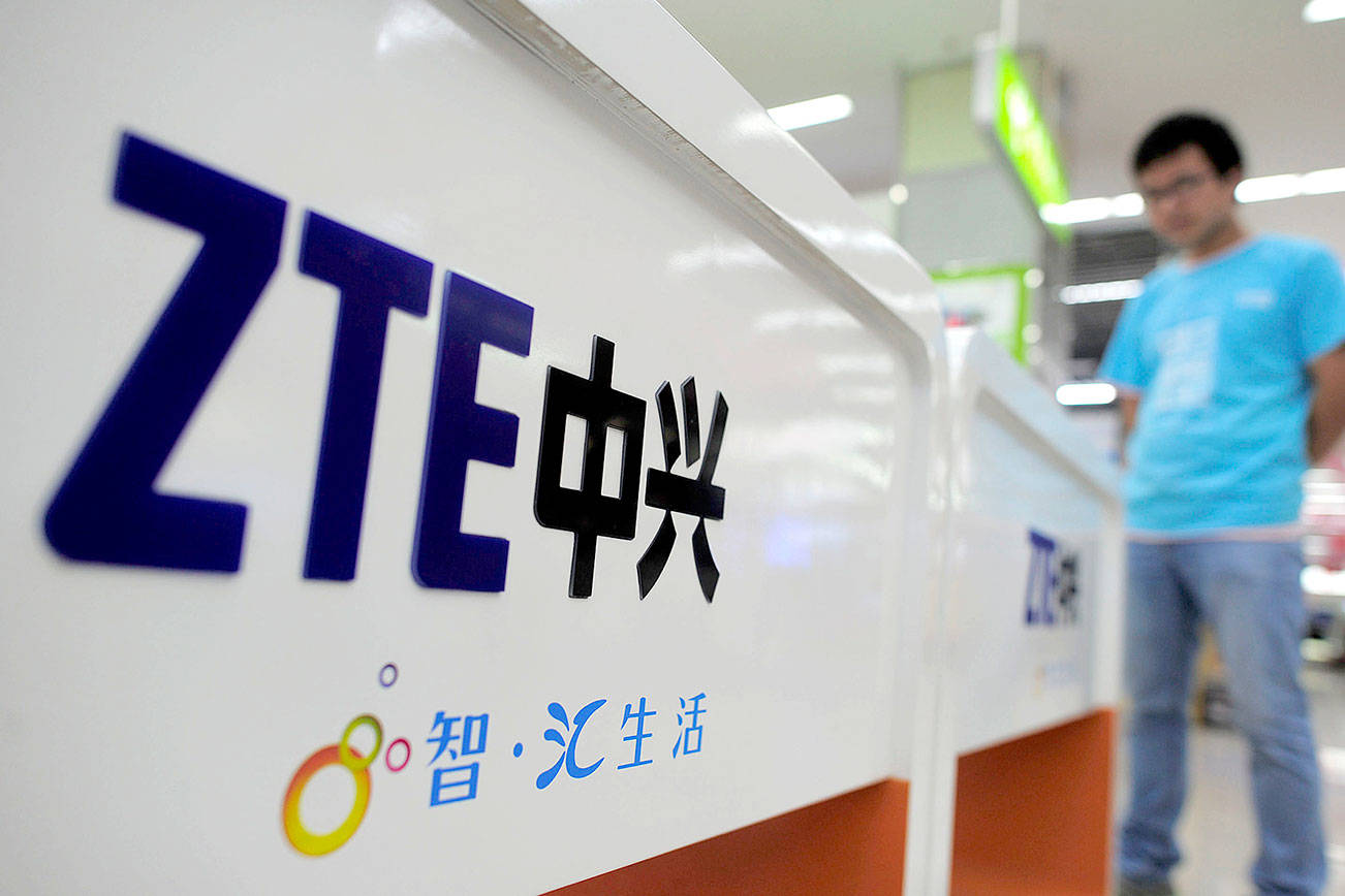 FILE - In this Oct. 8, 2012, file photo, a salesperson stands at counters selling mobile phones produced by ZTE Corp. at an appliance store in Wuhan in central China’s Hubei province. (Chinatopix Via AP, File)