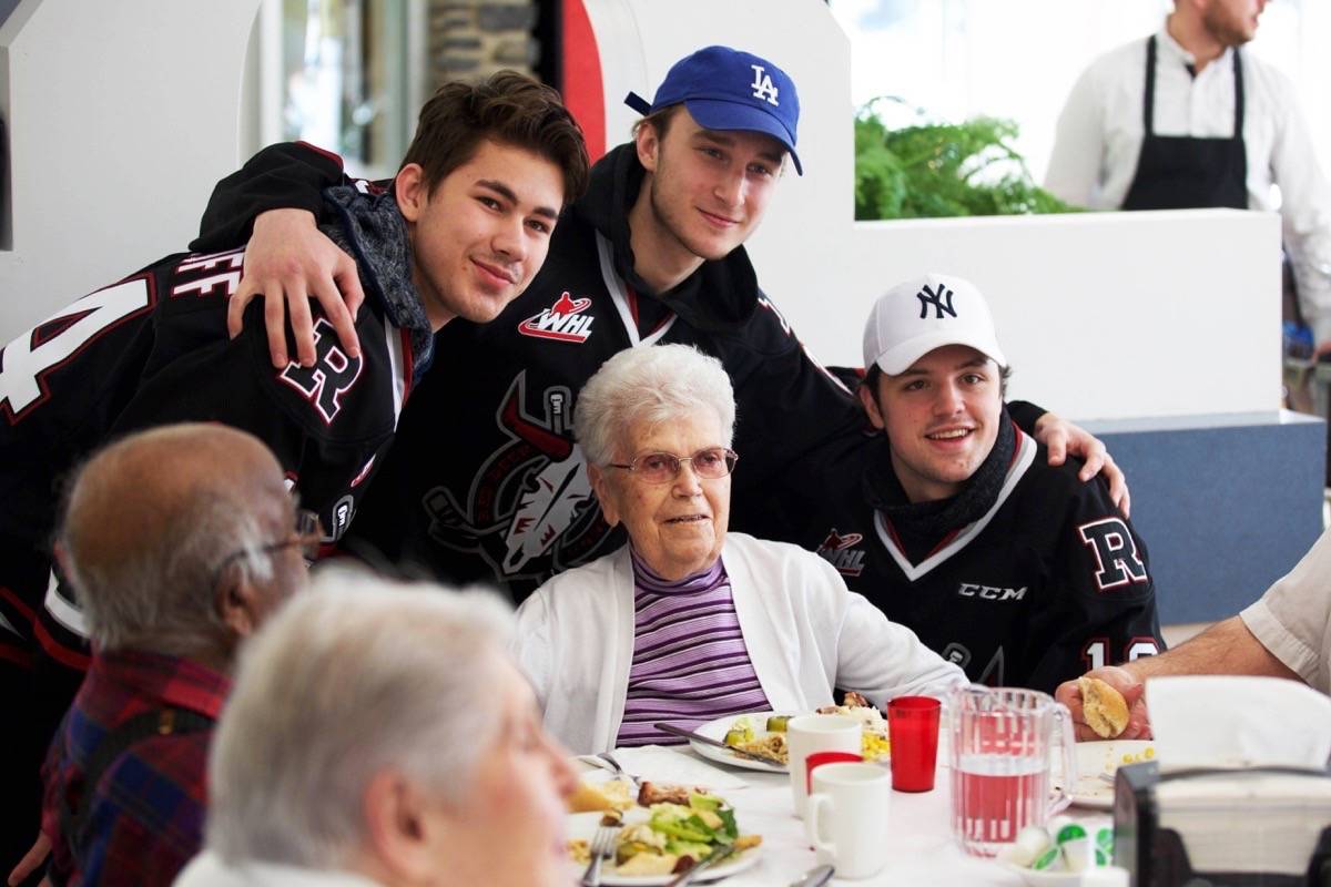 Red Deer Rebels players Alex Morozoff, Brett Davis and Cam Hausinger pose for a photo with 94-year-old Marion Paulson at the Bridges Community Living Centre, formerly the Piper Creek Foundation, Tuesday. Sherwin-Williams employees painted the main dining area at the Centre as a way to give back to the community. Robin Grant/Red Deer Express