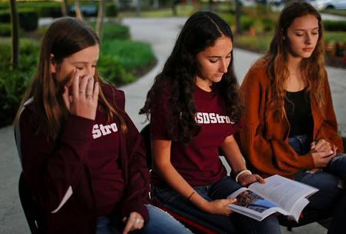 In this Wednesday, Jan. 16, 2019, photo, Brianna Fisher, 16, left, Leni Steinhardt, 16, center, and Brianna Jesionowski sit during an interview with The Associated Press about a new book called “Parkland Speaks: Survivors from Marjory Stoneman Douglas Share Their Stories,” in Parkland, Fla. Students and teachers from the Florida school where 17 died in February‚Äôs high school massacre wrote the raw, poignant book about living through the tragedy. (AP Photo/Brynn Anderson)