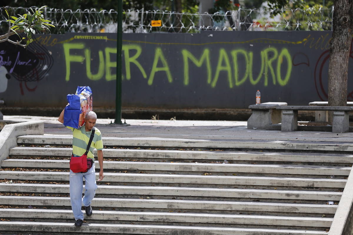 A man walks past graffiti on the wall of a vacant lot that reads in Spanish: “Get out Maduro,” referring to President Nicolas Maduro in Caracas, Venezuela, Thursday, Jan. 24, 2019. Venezuelans headed into uncharted political waters Thursday, with the young leader of a newly united and combative opposition claiming to hold the presidency and Maduro digging in for a fight with the Trump administration. (AP Photo/Fernando Llano)
