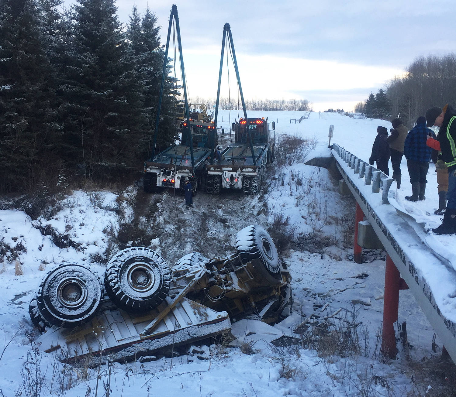 Emergency crews and two flat deck trucks from Calnash Trucking were used Friday morning to pull this large rock hauler out of the river. Alberta Environment was notified of the incident and that there was a small amount of diesel that entered the river. Photo submitted