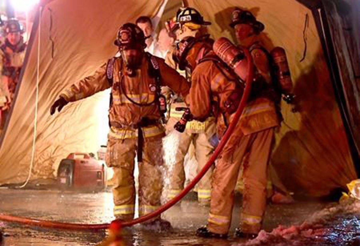 An Ottawa firefighter gets hosed down by a colleague outside a tent after they responded to the Steacie Building for Chemistry at Carleton University in Ottawa after reports of smoke coming from the building on Saturday, Jan. 26, 2019. (Justin Tang/The Canadian Press)