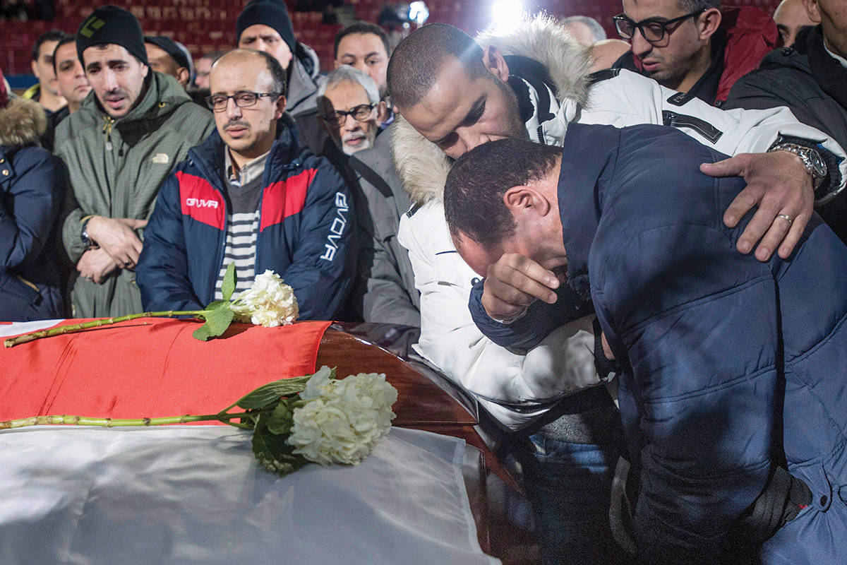 A man breaks down next to the caskets of three of the six victims of the Quebec City mosque shooting during funeral services at the Maurice Richard Arena in Montreal. (File photo by THE CANADIAN PRESS)