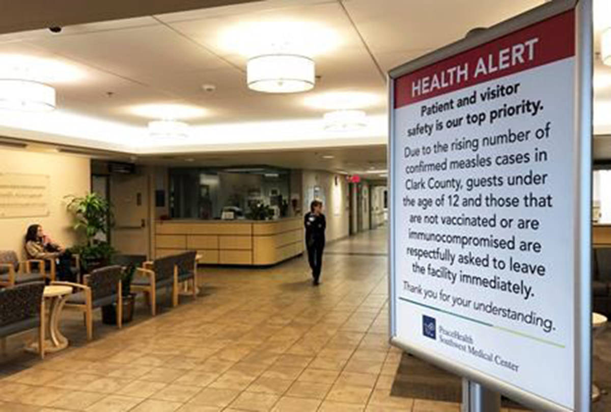 FILE - In this Jan. 25, 2019 file photo a sign prohibiting all children under 12 and unvaccinated adults stands at the entrance to PeaceHealth Southwest Medical Center in Vancouver, Wash. A measles outbreak that has sickened more than 40 people in the Pacific Northwest has prompted a call to eliminate a “philosophical” vaccine exemption that’s resulted in 4 percent of children in Washington state to attend school without their routine childhood shots. (AP Photo/Gillian Flaccus, File)