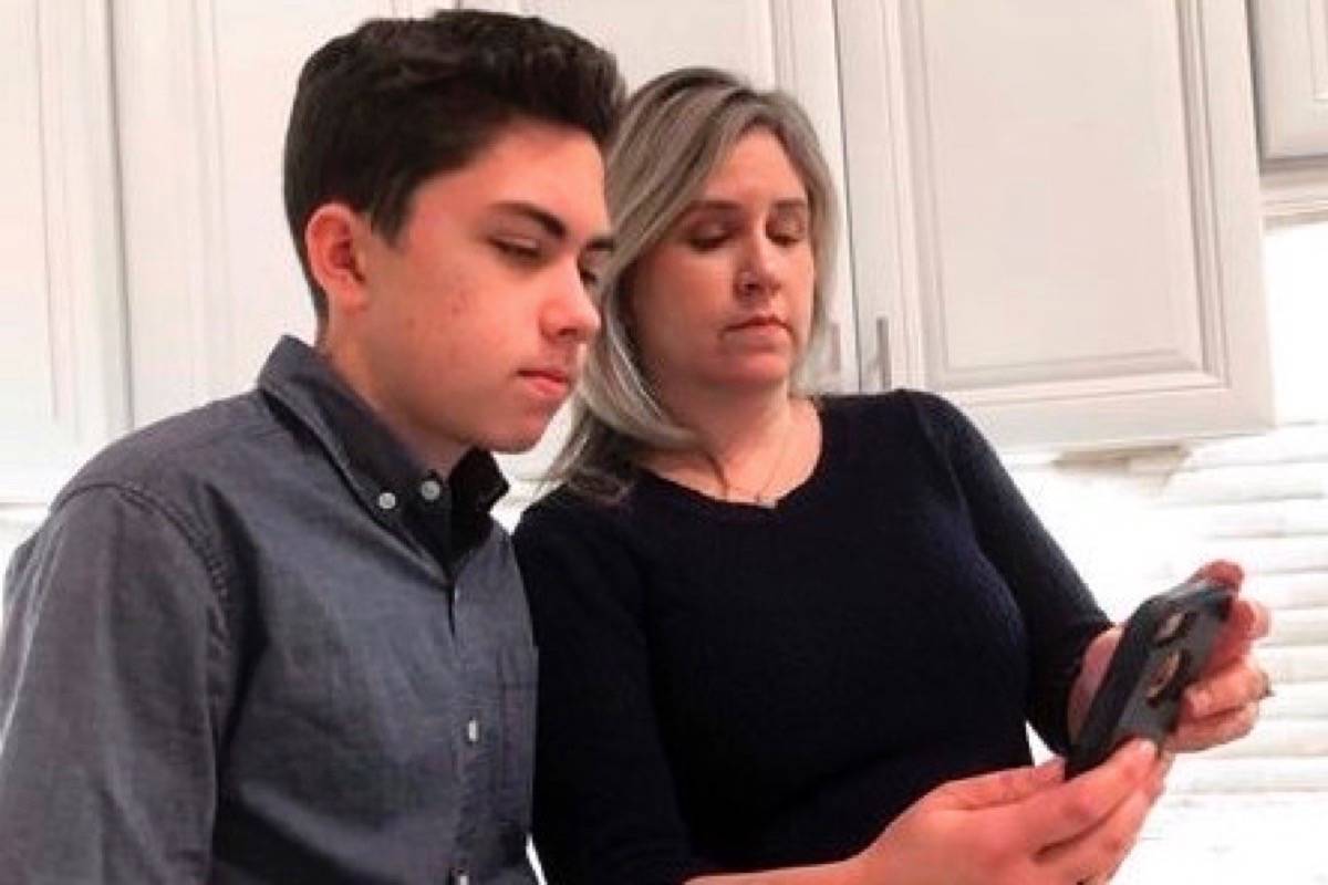 Grant Thompson and his mother, Michele, look at an iPhone in the family’s kitchen in Tucson, Ariz., on Thursday, Jan. 31, 2019. (AP Photo/Brian Skoloff)