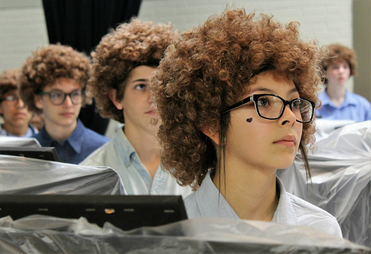 Madison Middle School art student Ariceli Martinez, wearing her Bob Ross wig, listens to the artist speak on a video screen before painting began on Flash Bob Flash Mob Day on Feb. 7, 2019 in Abilene, Texas The students donned their curliest wigs and painted little trees onto canvases to pay homage to the late painter Bob Ross. Teacher Brady Sloane said the idea came about because she wanted to reward Advanced Placement students who had been stressed out over recent projects and grades. (Greg Jaklewicz/The Abilene Reporter-News via AP)