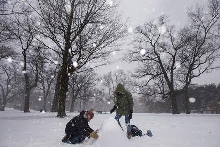 Rafael Ravara, left, and Alano Silva, take advantage of the winter storm to build their first snowman at High Park in Toronto on Tuesday, February 12, 2019. (THE CANADIAN PRESS/ Tijana Martin)