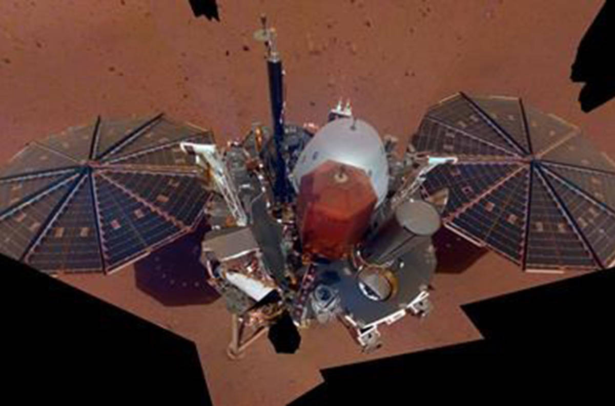 This Dec. 6, 2018 image made available by NASA shows the InSight lander. The scene was assembled from 11 photos taken using its robotic arm. The two white stalks between the center and the solar panels are weather sensors. Starting Tuesday, Feb. 19, 2019, NASA‚Äôs Jet Propulsion Laboratory is posting the high and low temperatures online, along with wind speed and atmospheric pressure from the InSight lander. (NASA via AP)