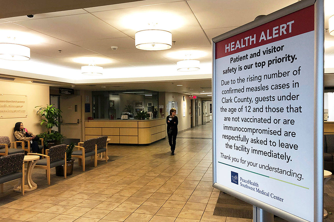In this Jan. 25, 2019 file photo, a sign prohibiting all children under 12 and unvaccinated adults stands at the entrance to PeaceHealth Southwest Medical Center in Vancouver, Wash. (AP Photo/Gillian Flaccus, File)