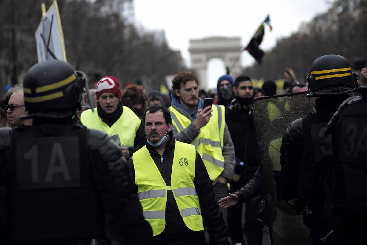 Yellow vest protesters walk down the famed Champs Elysees avenue to keep pressure on French President Emmanuel Macron’s government, for the 13th straight weekend of demonstrations, in Paris, France, Saturday, Feb. 9, 2019. (AP Photo/Kamil Zihnioglu)