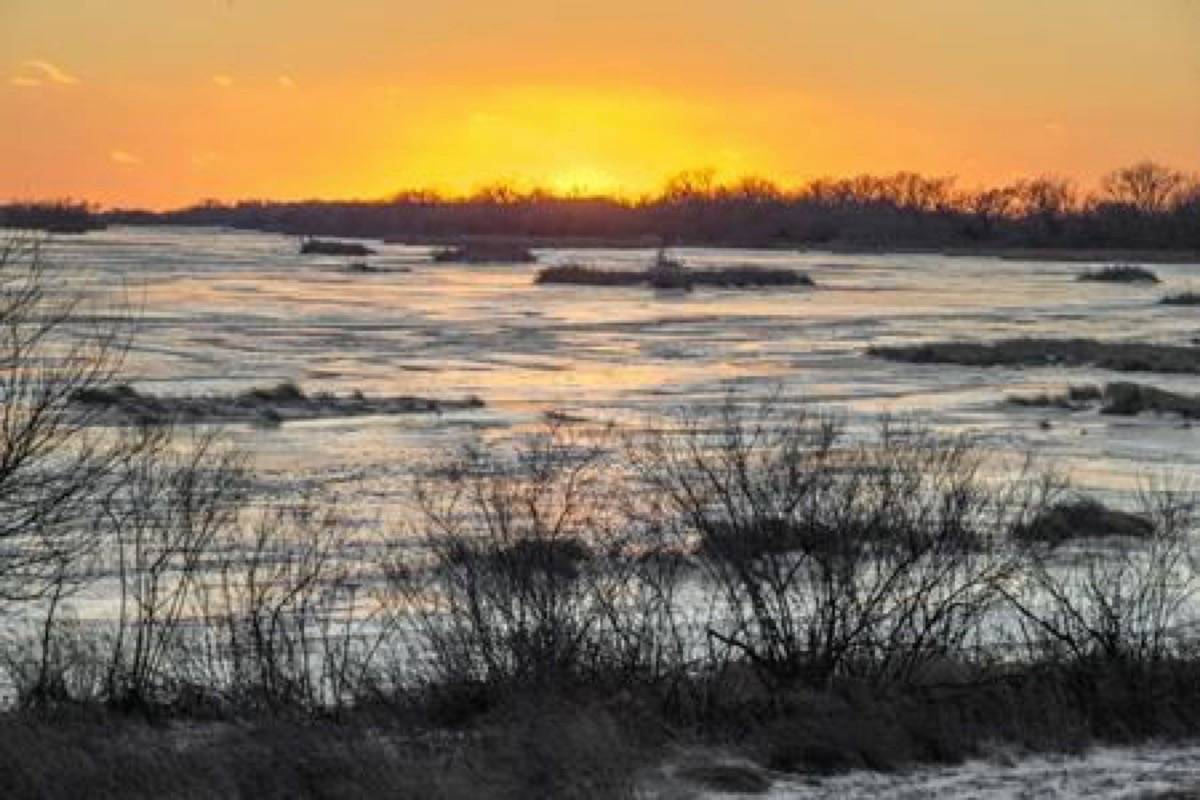 In this Feb. 7, 2019 photo, the sun sets behind the ice-covered Platte River in Columbus, Neb. Mentioning climate change can kill a conversation. But a new Alberta project is using the topic to start one - and has shown people from geologists to farmers to environmentalists they have more in common than they thought. THE CANADIAN PRESS/AP/Nati Harnik