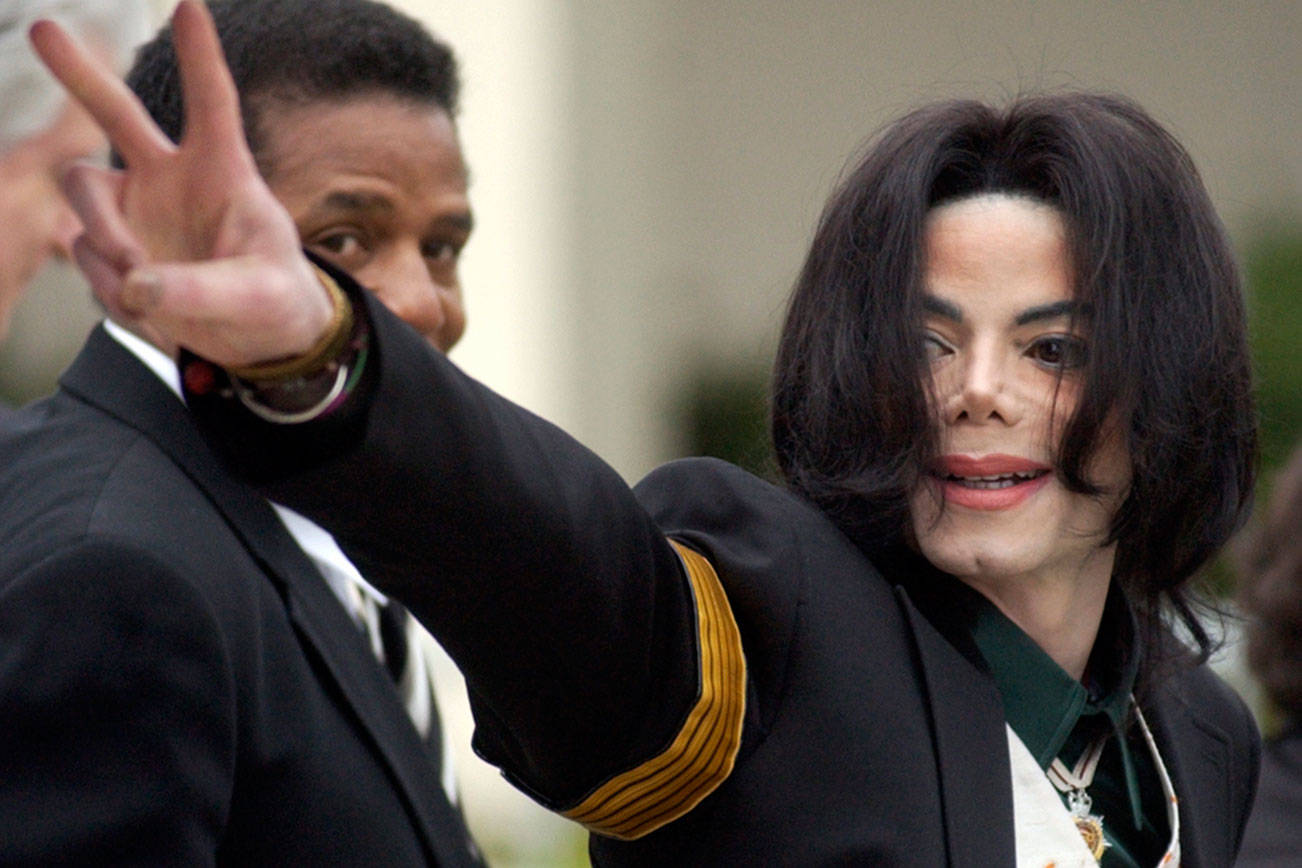 FILE - In this March 2, 2005 file photo, pop icon Michael Jackson waves to his supporters as he arrives for his child molestation trial at the Santa Barbara County Superior Court in Santa Maria, Calif. A new documentary premiering Sunday on HBO, “Leaving Neverland,” is about the abuse allegations of two men, Wade Robson and James Safechuck, who had previously denied Jackson molested them and supported him to authorities and in Robson’s case, very publicly. (AP Photo/Michael A. Mariant, File)